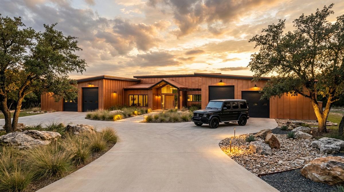 Modern countryside home with warm timber cladding and a landscaped stone driveway at sunset